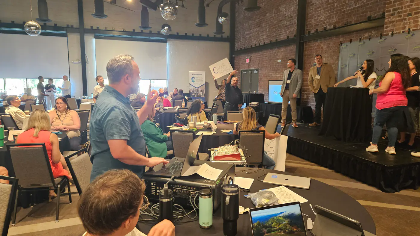 The game in play. The host on stage with the microphone and the questions on her phone, Team F on the right, and the game itself being run from the laptop at the back.